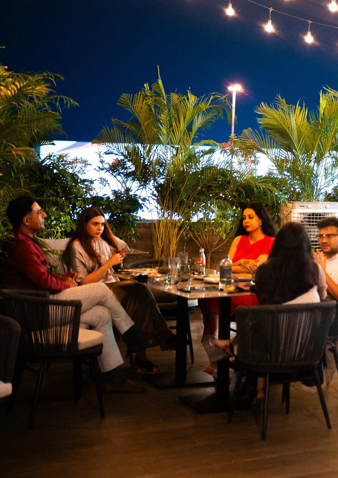 Guests at a table on a terrace under string lights