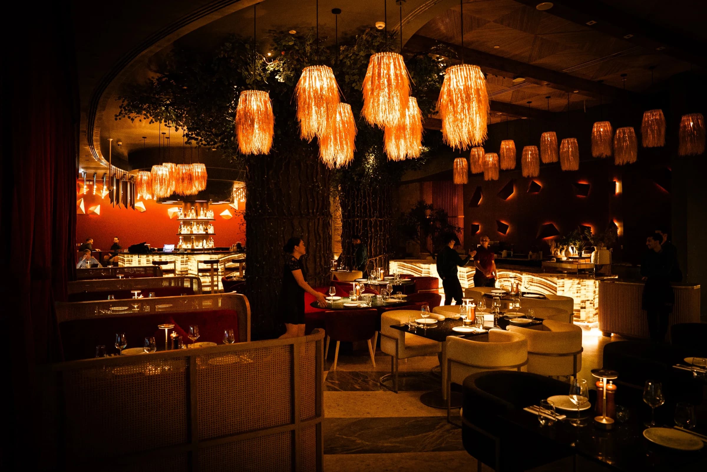 Restaurant dining room at night, straw lamps over set tables